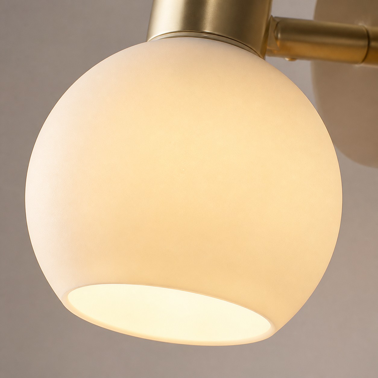 Nahaufnahme eines warm leuchtenden Glasschirms an einer goldenen Wandleuchte
