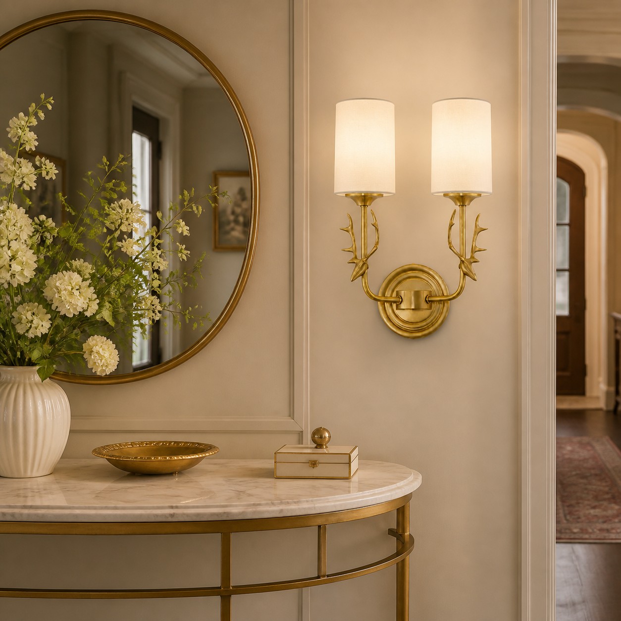Two-light brass antler wall sconce with white glass shades above a console