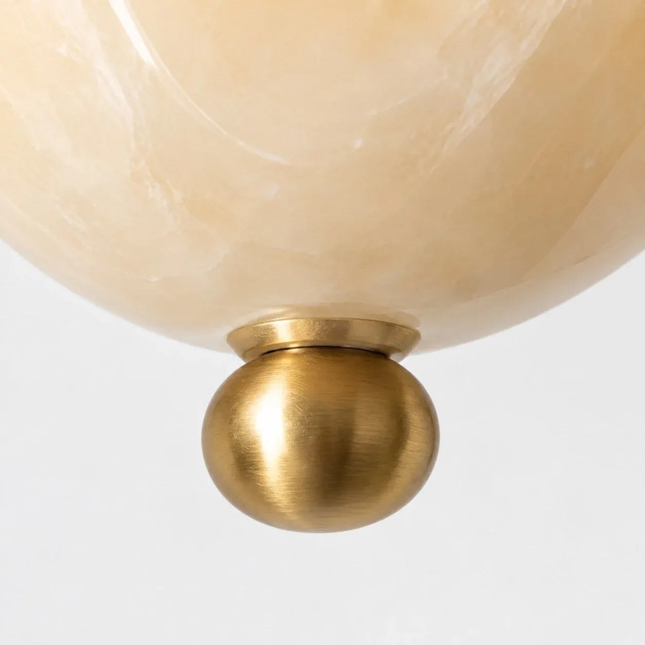 Brushed brass ball finial at the base of the glass shade