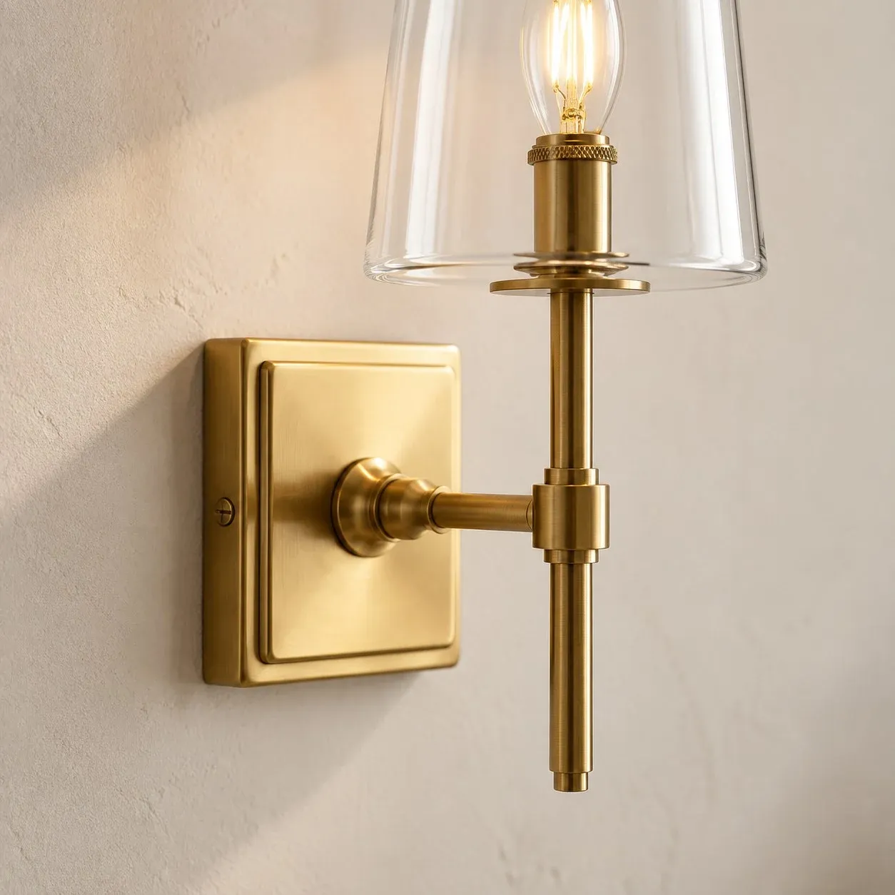 Square brass backplate sitting on the wall with a short arm