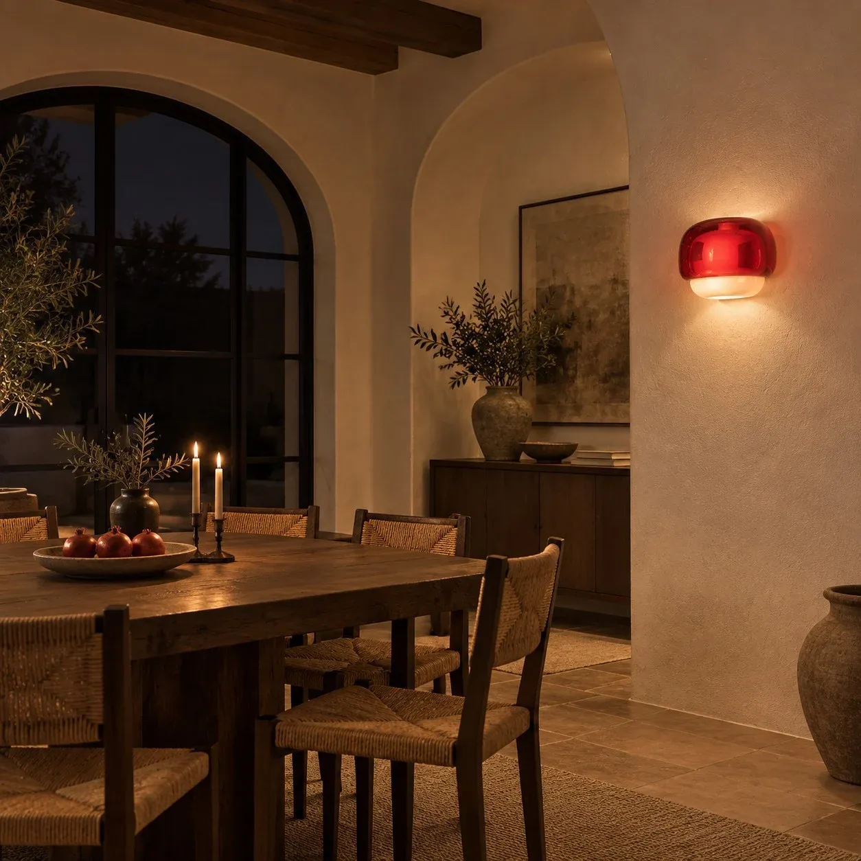 Burgundy glass wall sconce glowing beside a dining table
