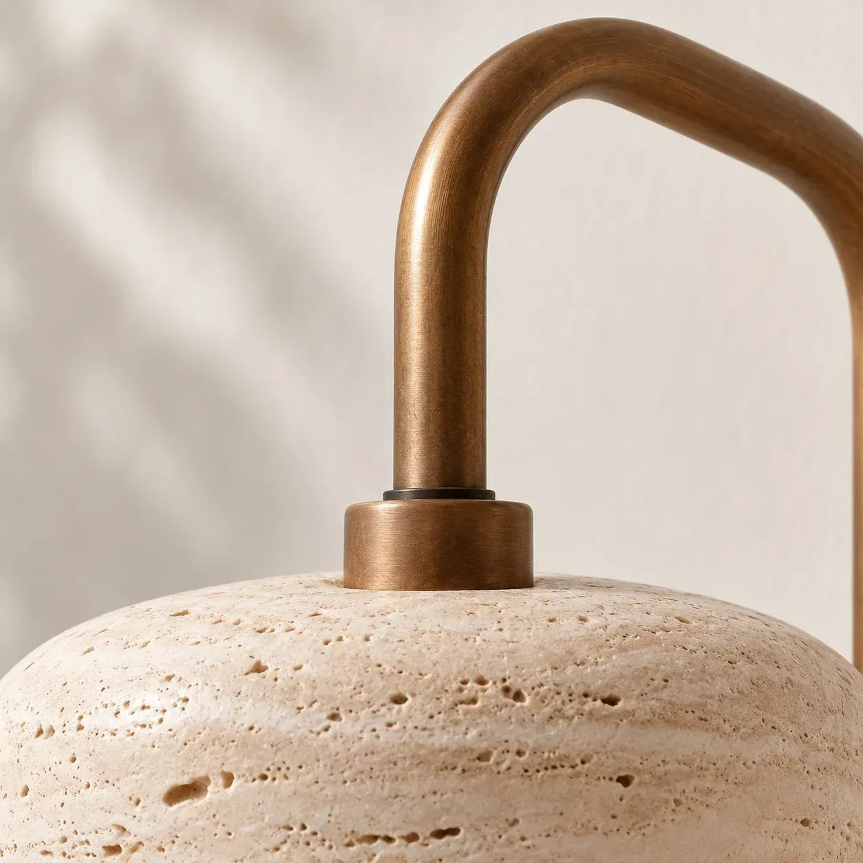 Brass arm joint on top of a rounded travertine shade