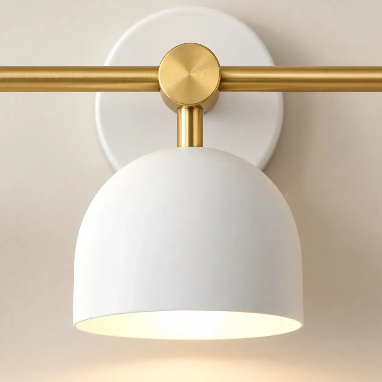 Close view of a white dome shade, pale interior, and brushed brass center joint