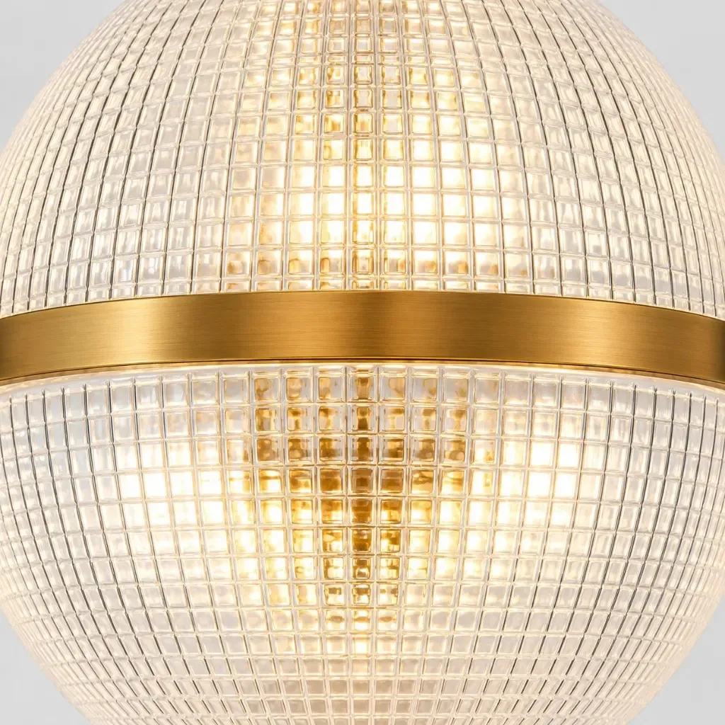 Een bol van gehamerd, helder glas, doorsneden door een geborstelde gouden band, van binnenuit verlicht.