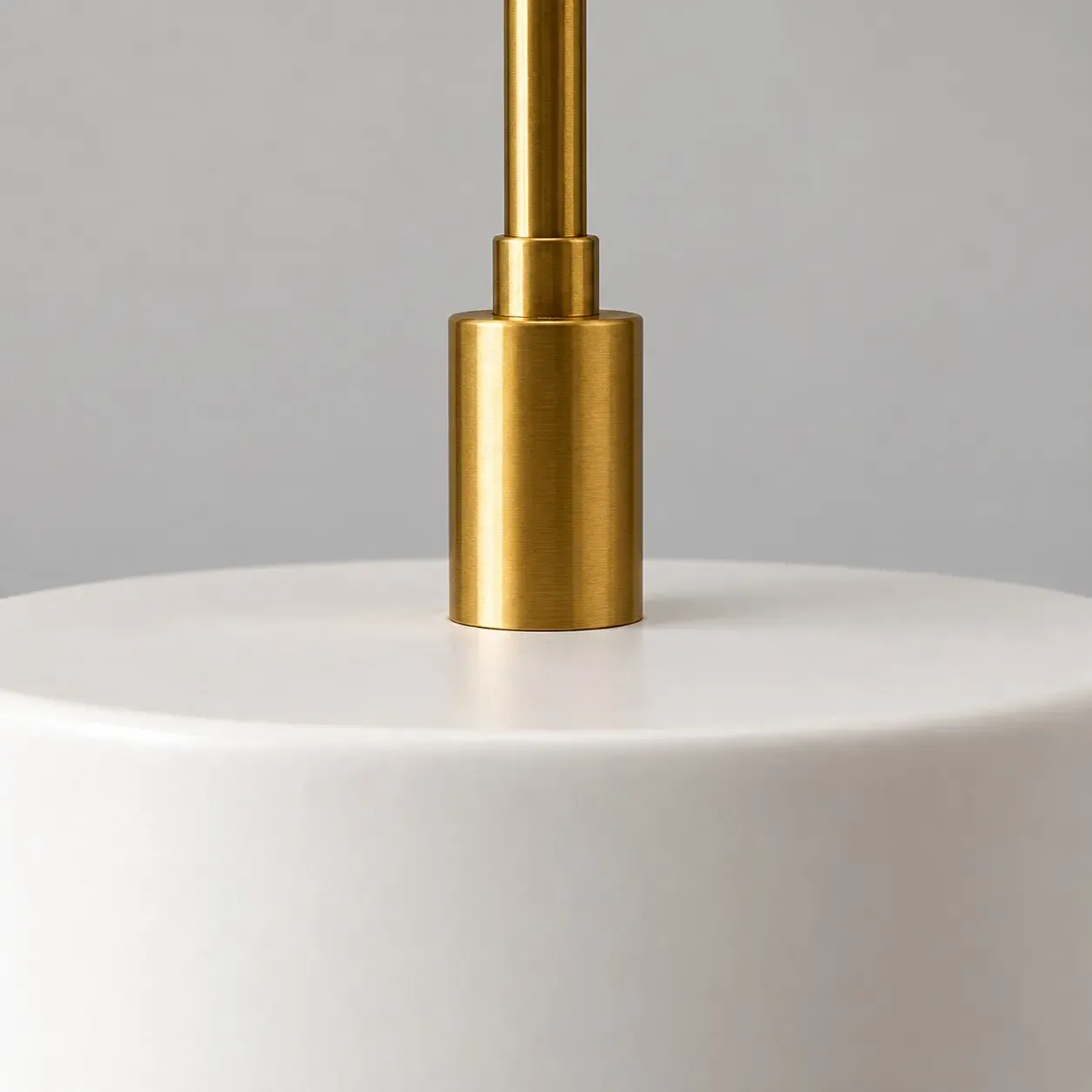 Gros plan sur le collier métallique où la tige rejoint l'abat-jour en porcelaine blanche