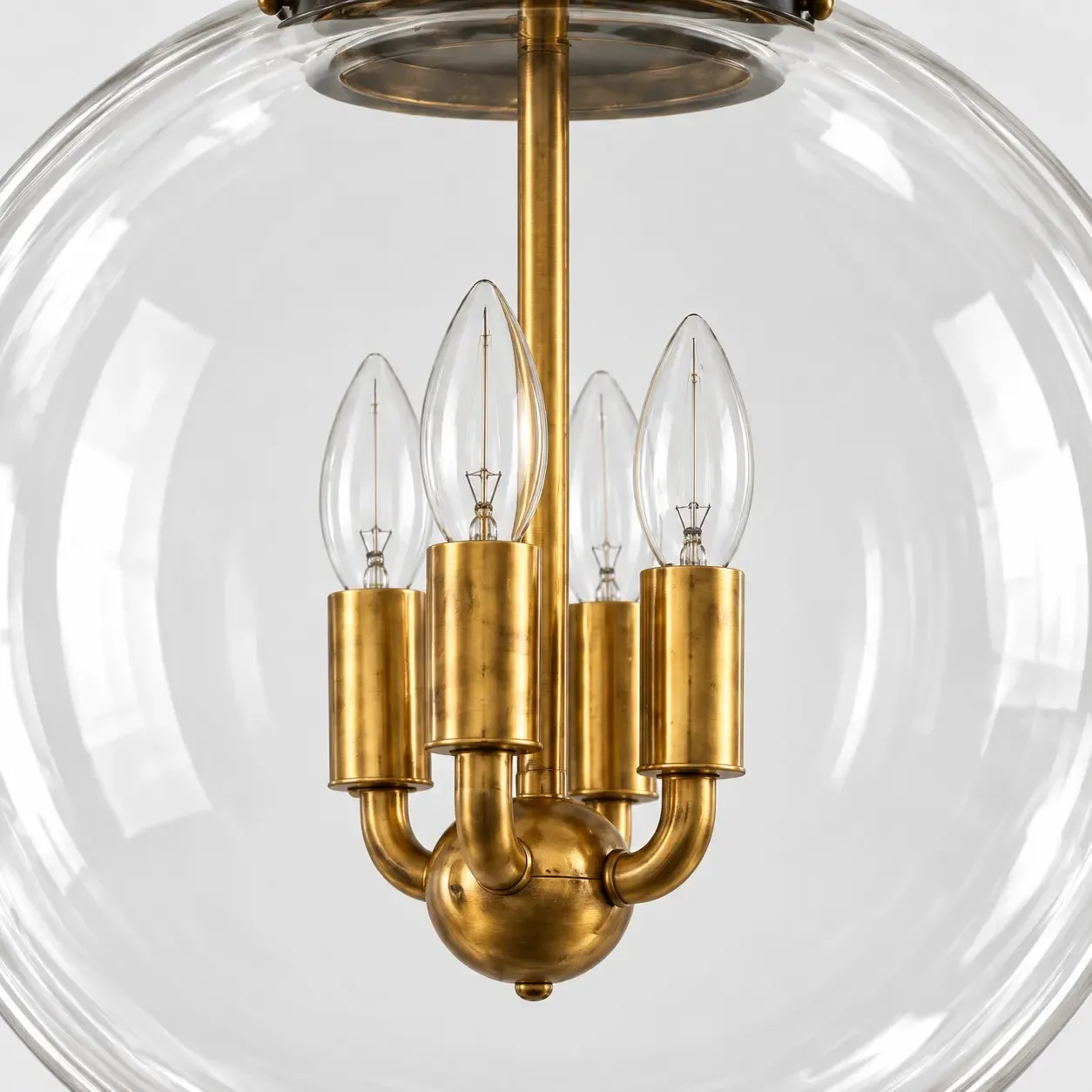 Four brass arms holding candelabra bulbs inside the clear glass globe