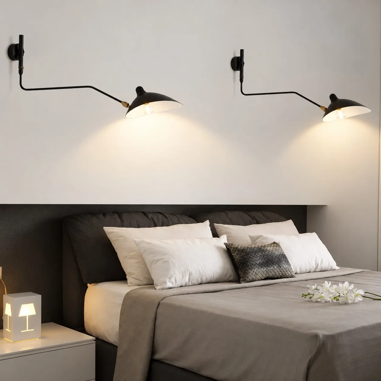 Two black one-light wall sconces above a bed