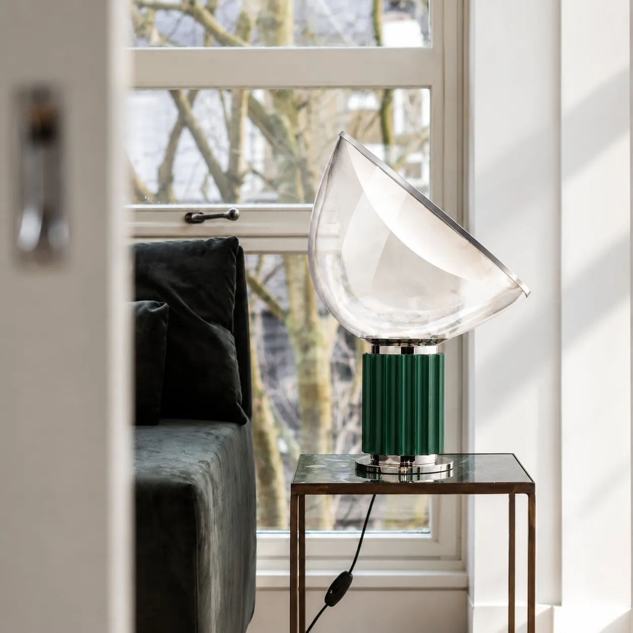Dark green glass bowl lamp on a table by a window