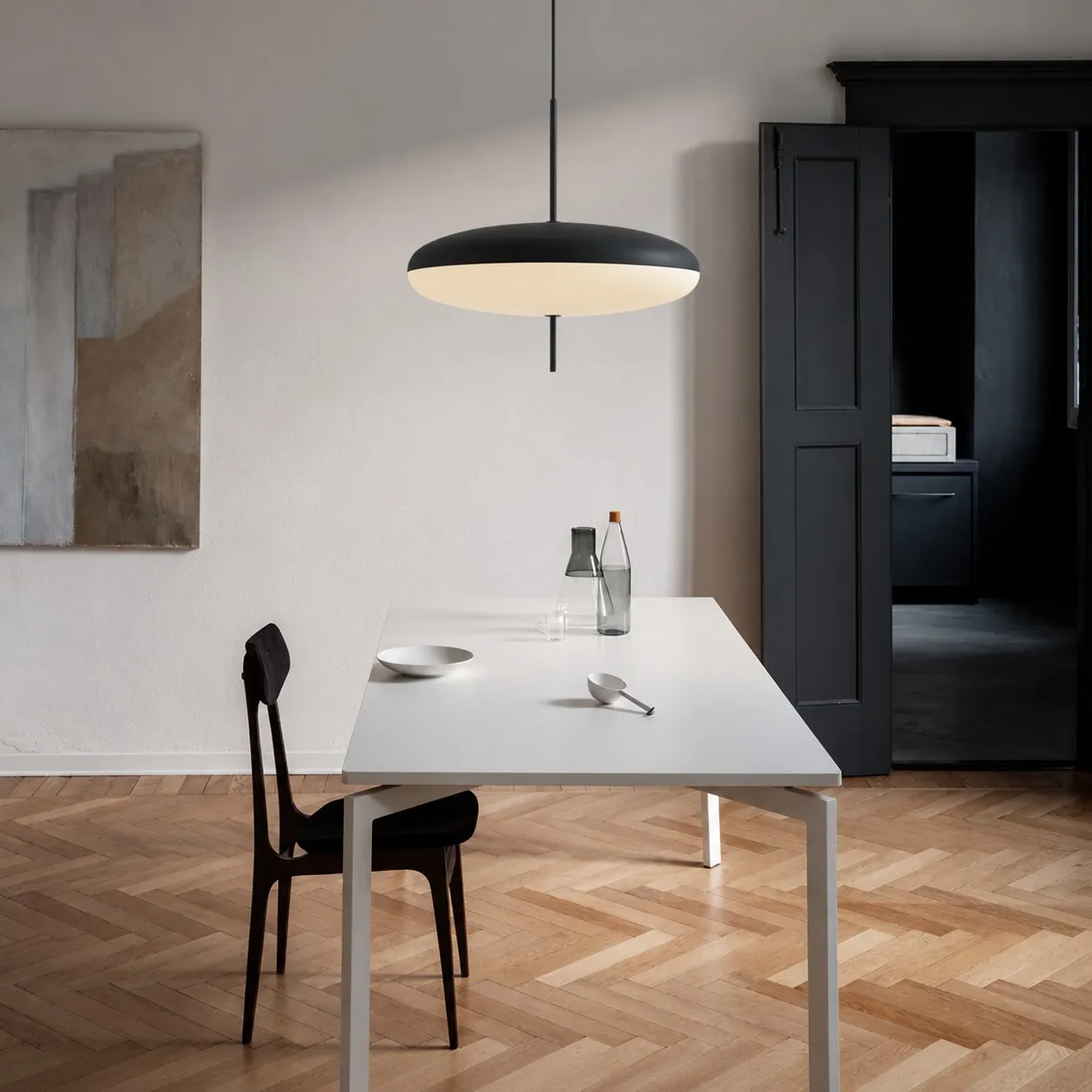 Black elliptical pendant above a white dining table