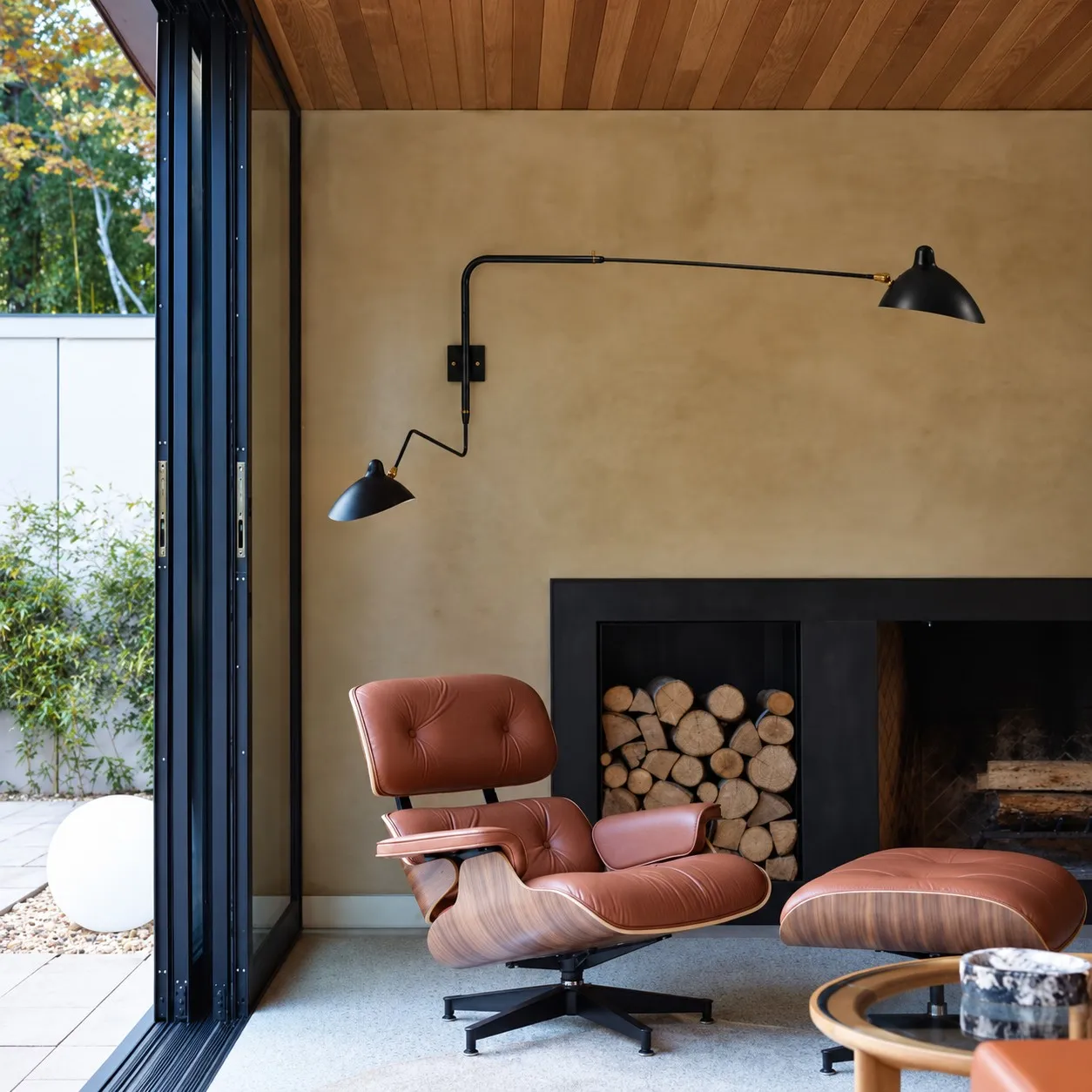 Black two-light wall sconce above a lounge chair