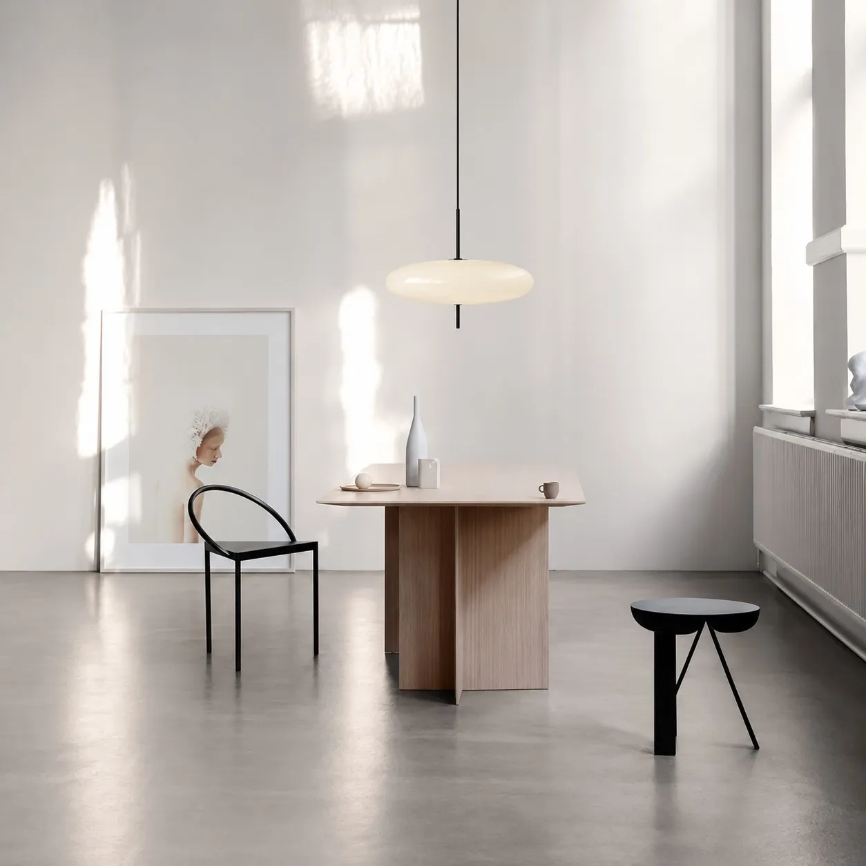 White elliptical pendant above a wood dining table