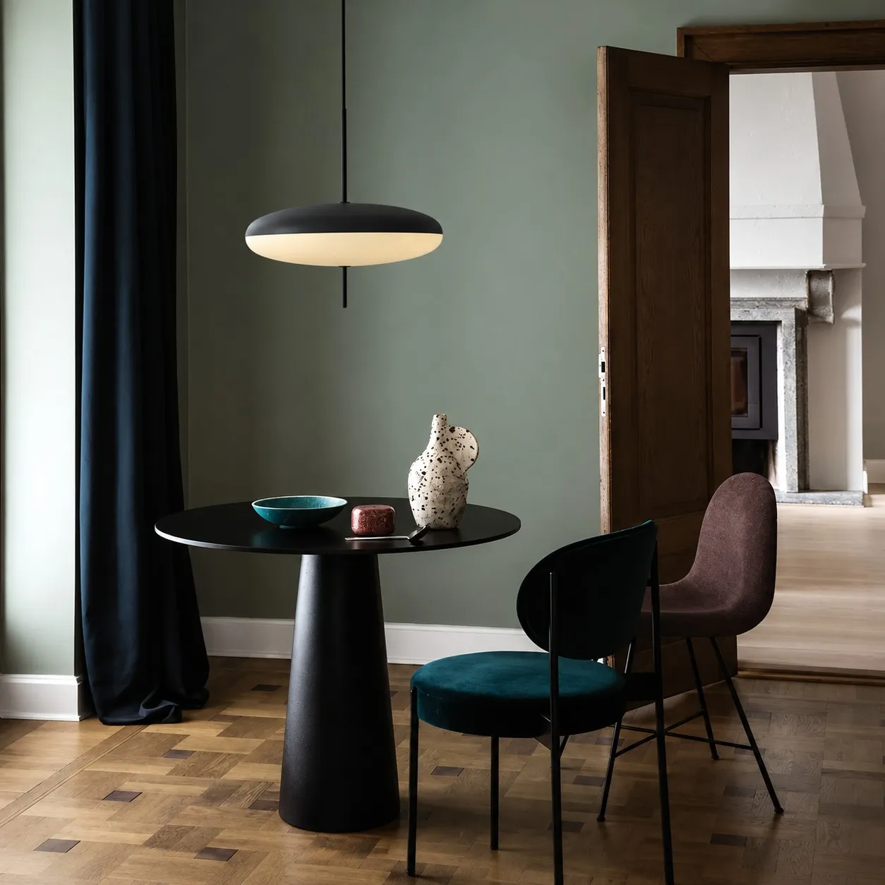 Black elliptical pendant above a black pedestal table