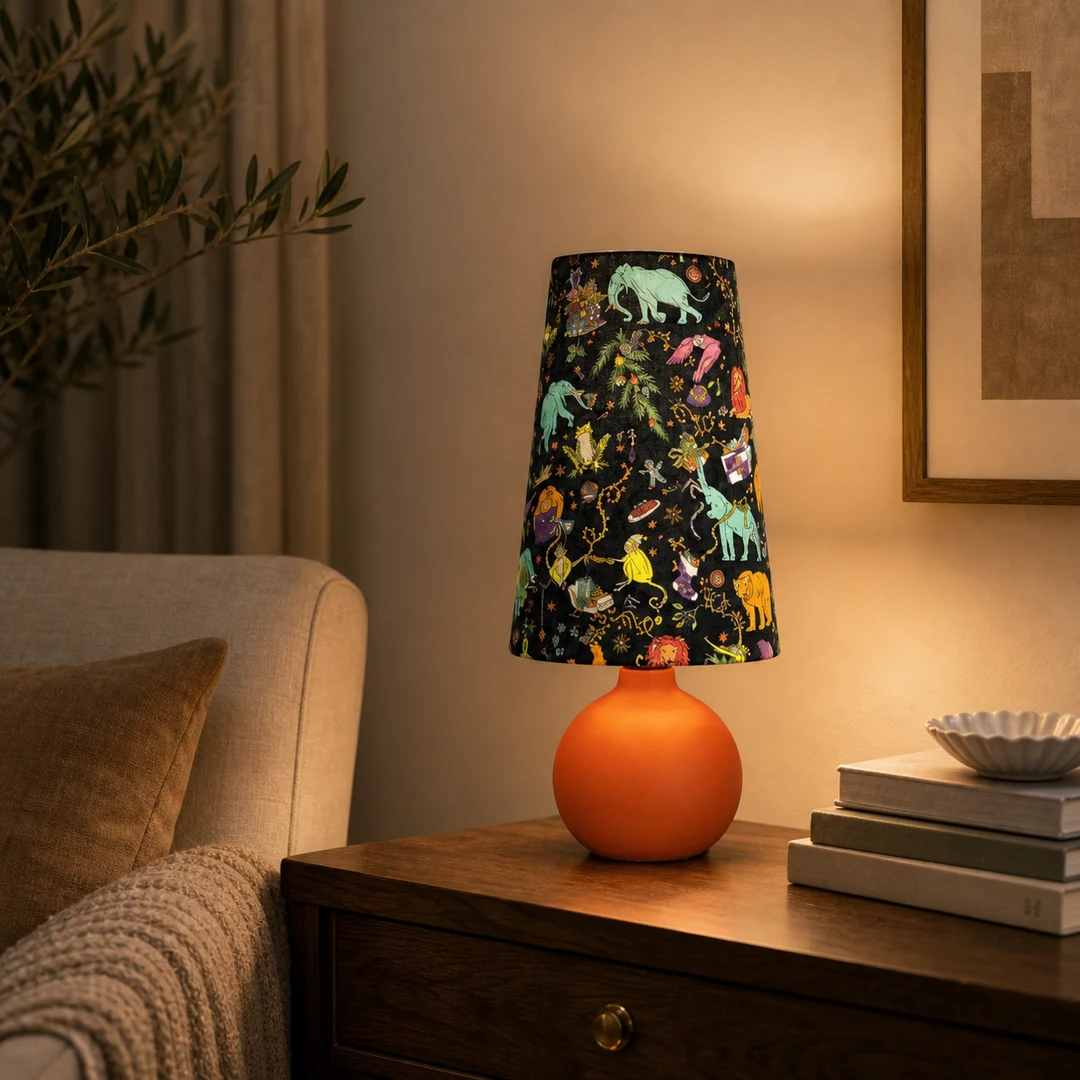Lámpara de mesa de tela colorida colocada sobre una mesita de noche en una habitación cálida.